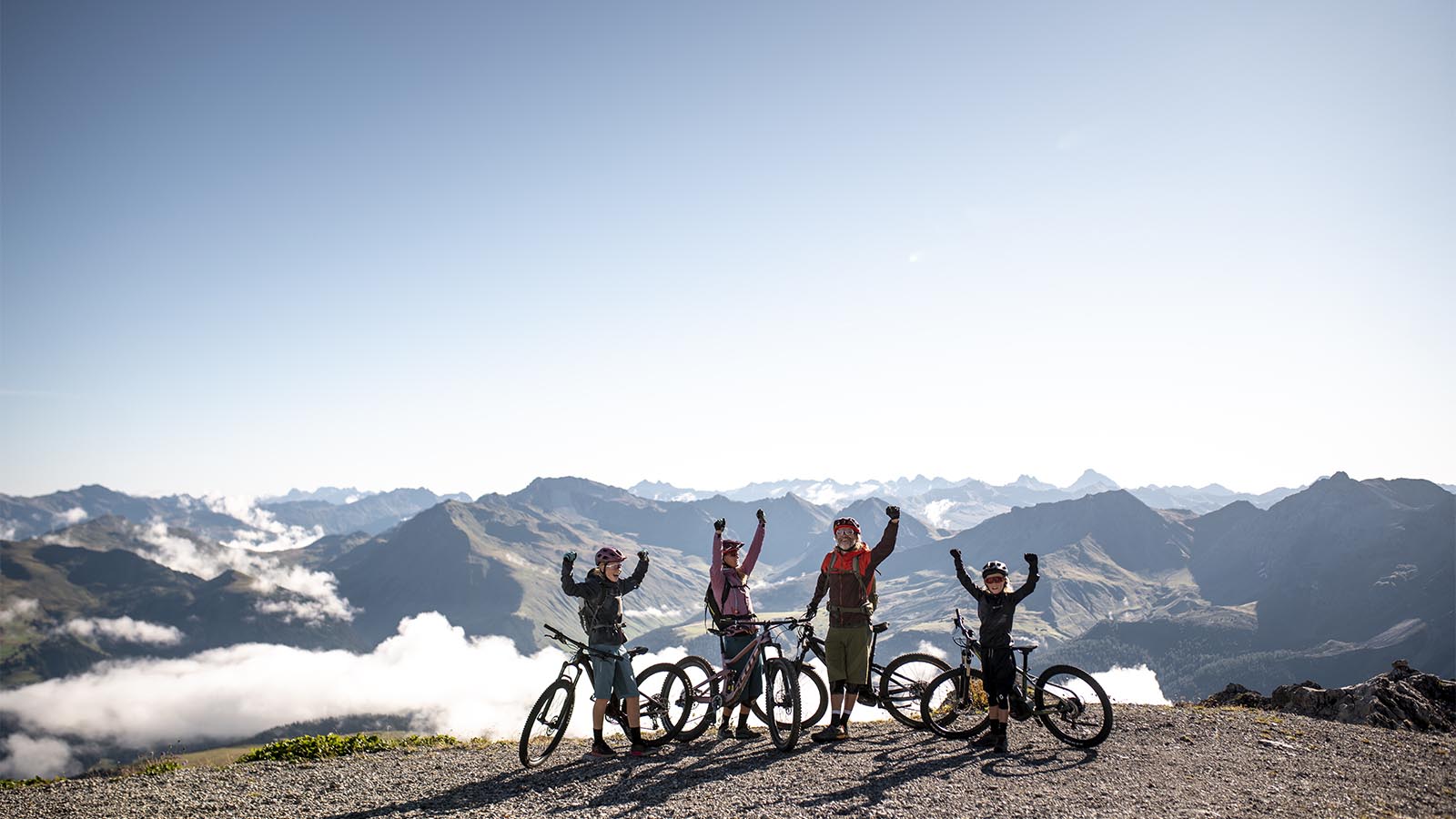 Familia con e-bikes en un mirador de alta montaña sobre un mar de nubes