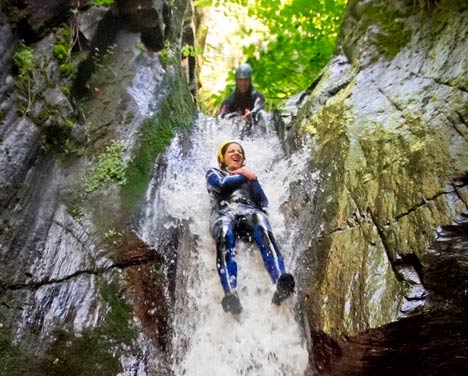 Persona deslizándose por un tobogán natural de agua en un barranco del Val d'Aran