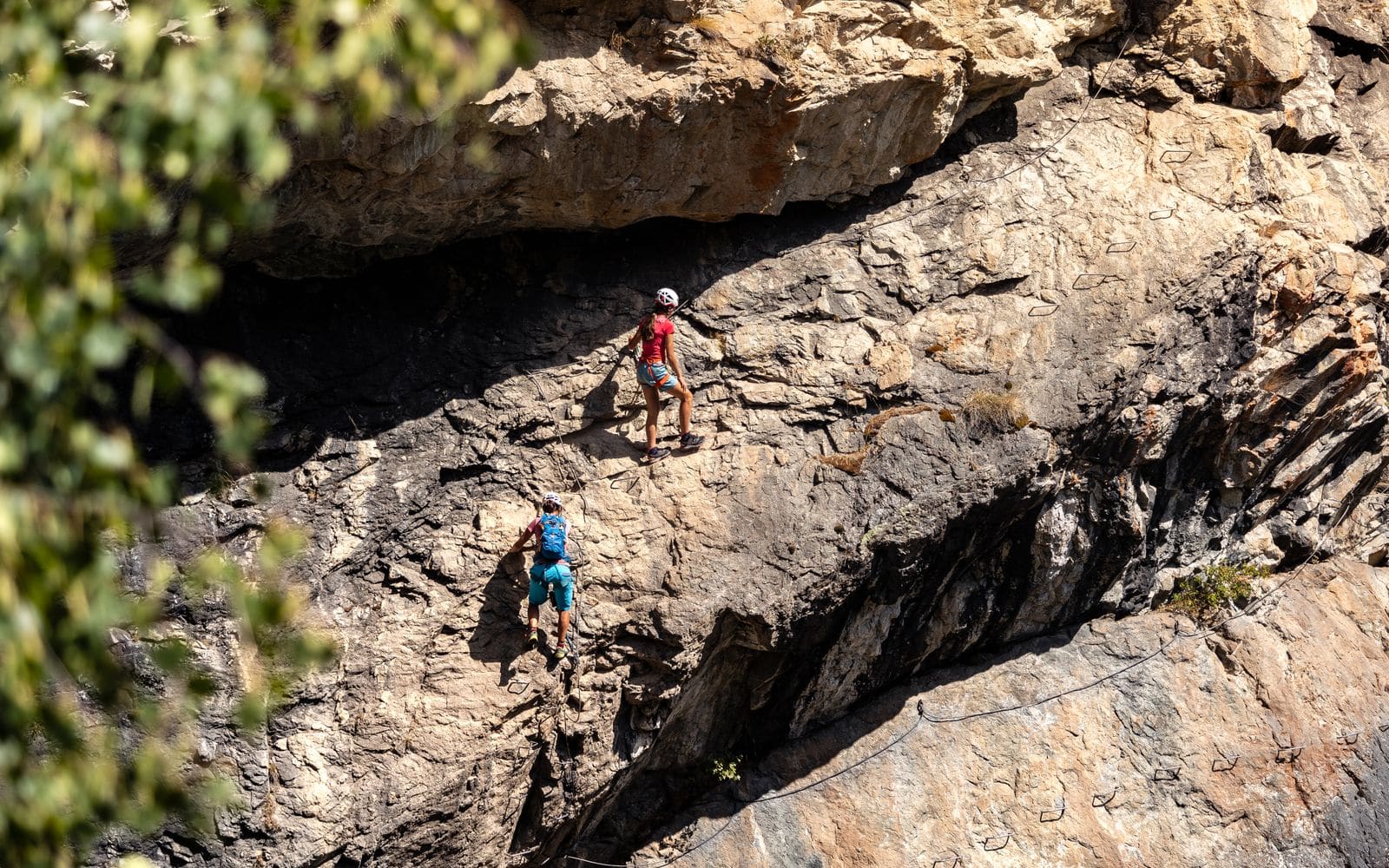 Persona ascendiendo una via ferrata equipada con clavijas de acero sobre una pared de roca