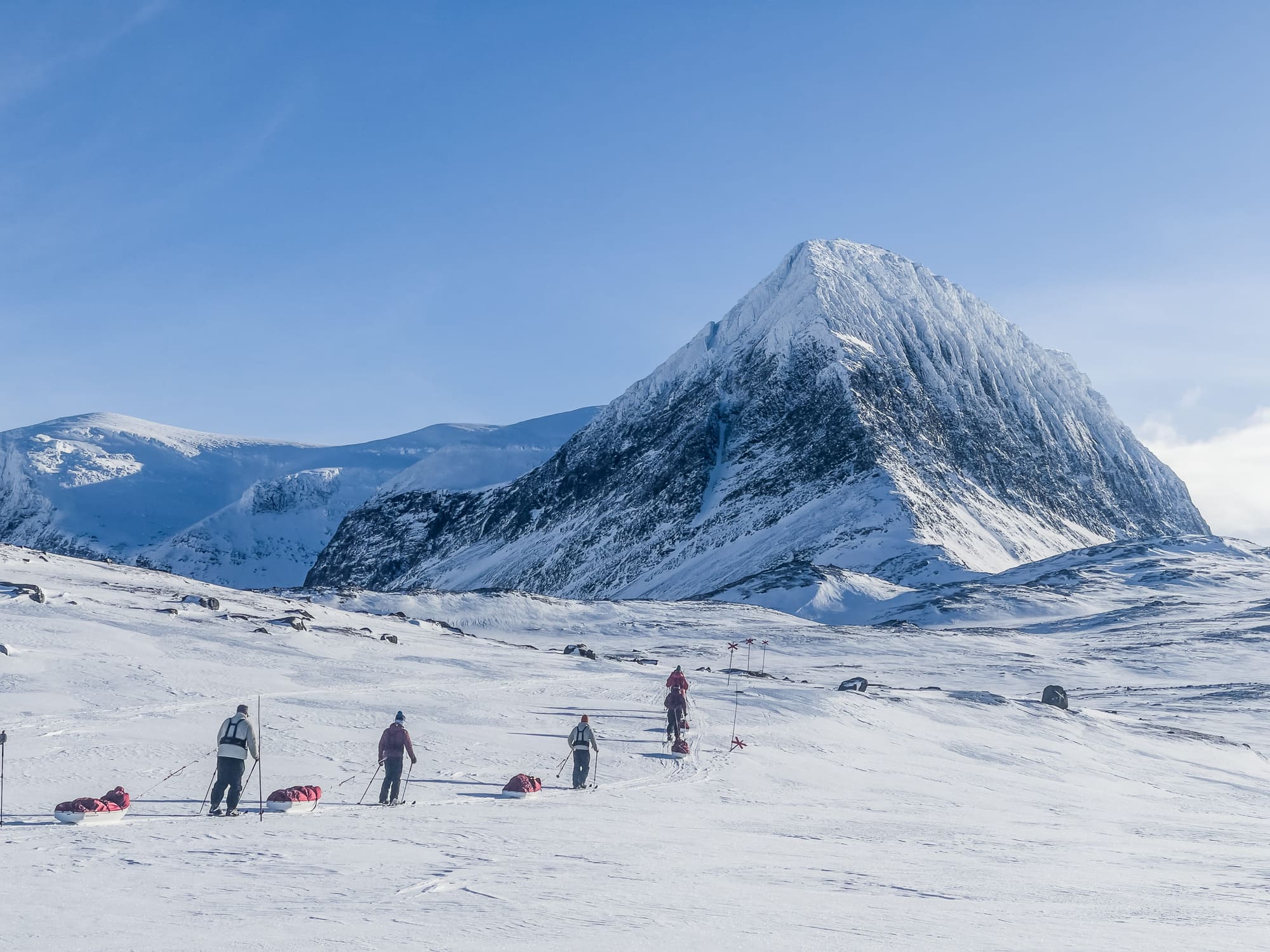 Grupo esquiando con pulka por un valle nevado en la Laponia sueca